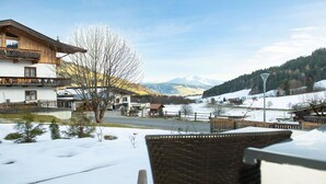 Un quartier résidentiel où le sol est recouvert de neige, avec une rivière et des montagnes en arrière-plan.