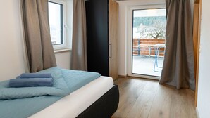 Een slaapkamer met een bed, een raam en uitzicht op een buitenruimte.