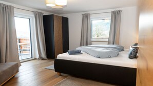 Een slaapkamer met een bed, een kledingkast, een raam en uitzicht op de omgeving.