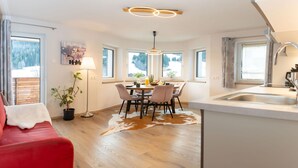 Een moderne keuken met een eethoek, grote ramen en een rode bank.