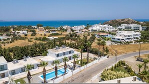 Ein modernes Resort mit Schwimmbad, Palmen und Meerblick.