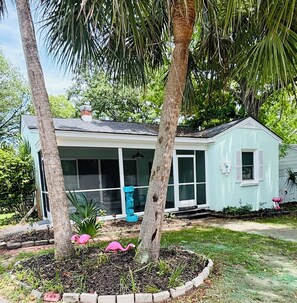 A light blue house with a covered porch, a brick chimney, and a small garden with flamingo statues. - Seahorse Villa.3 Bedroom House. (Myrtle Beach)