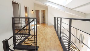 A spacious interior with a wooden floor, black metal railings, and a skylight. - Villa Solanne - Garden, pool & comfort / 10 travellers (Narrosse)