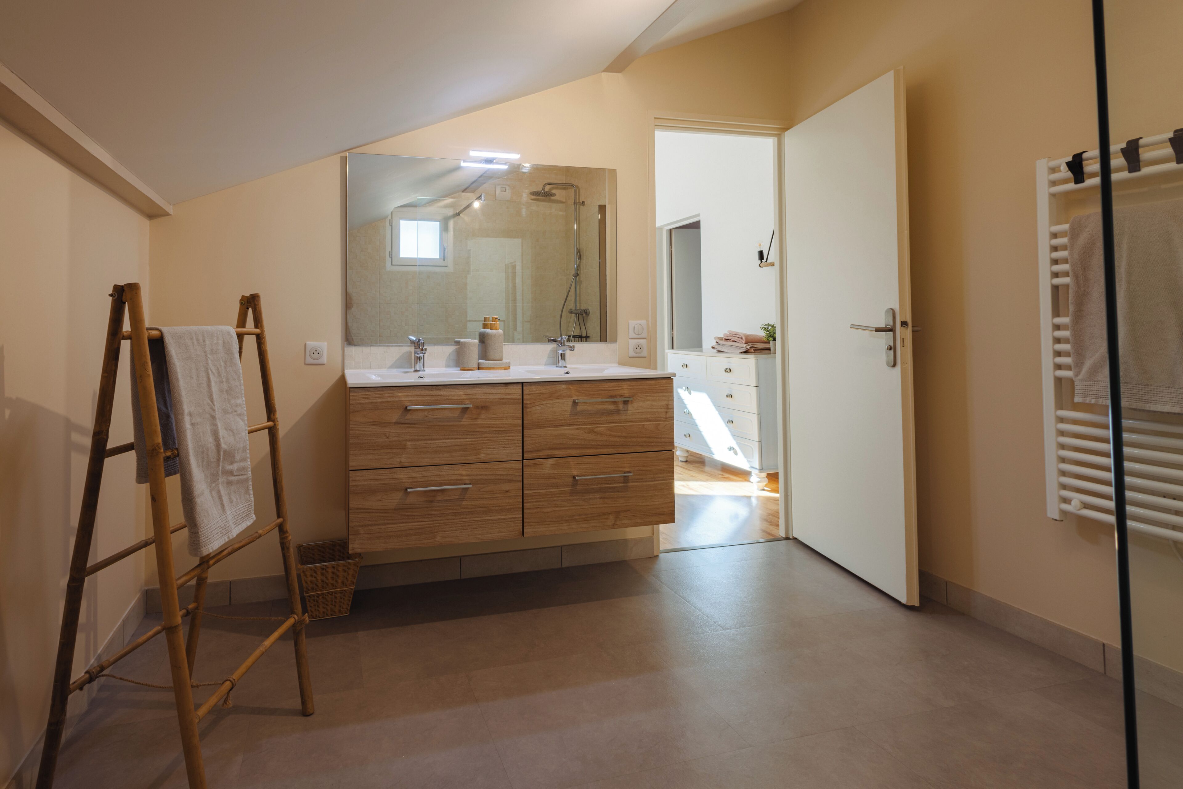 A bathroom with a wooden vanity, a large mirror, and a towel rack.