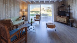 A room with a sofa, chairs, a table, a television, and a sliding glass door to the outside. - Villa Solanne - Garden, pool & comfort / 10 travellers (Narrosse)