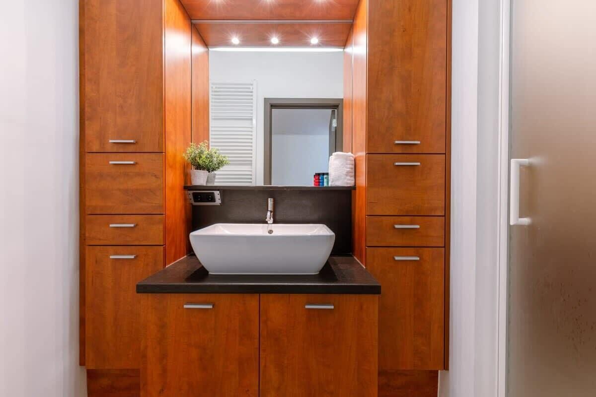 Un baño con tocador de madera, un lavabo blanco y un espejo encima.