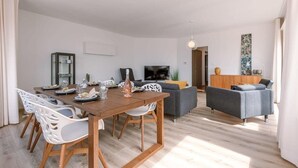 A modern living room with a dining area, a flat-screen TV, and a grey sofa. - Waterfront retreat w/ Wifi & workspace (Middelkerke)