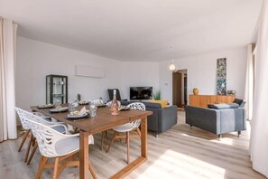 A modern living room with a dining area, a flat-screen TV, and a grey sofa. - Waterfront retreat w/ Wifi & workspace (Middelkerke)