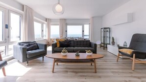 A modern living room with a sofa, armchair, and coffee table, large windows, and a view of the sea. - Waterfront retreat w/ Wifi & workspace (Middelkerke)