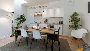 Eine moderne Küche mit weißen Schränken, einem Holztisch und vier Stühlen.