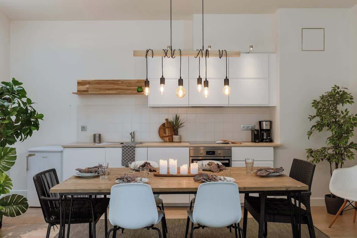 A modern kitchen with white cabinetry, a wooden dining table, and black chairs.