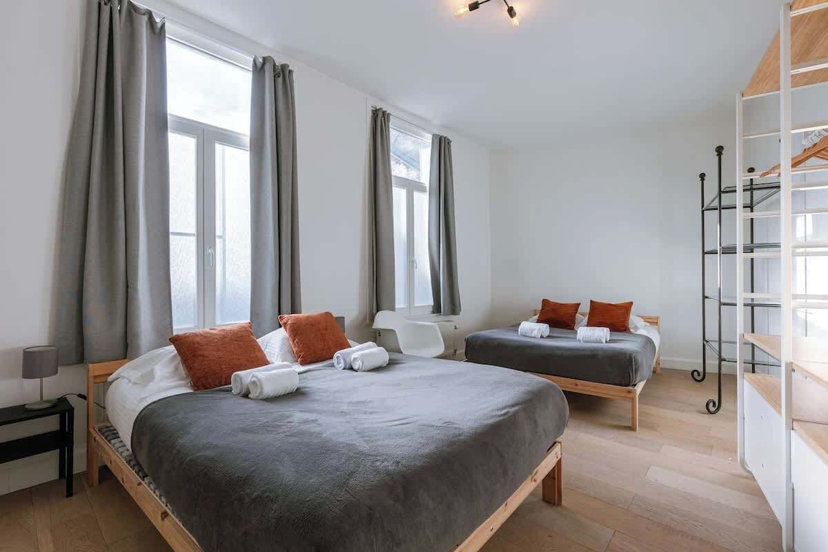 A hotel room with two beds, a desk, a chair, and a wardrobe.