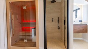 A modern bathroom with a glass-enclosed shower, a wooden vanity, and a visible toilet. - Coastal apartment w/ sauna & balcony (Cadzand)