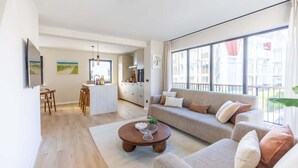 A modern living room with a sofa, coffee table, and dining area. - Coastal apartment w/ sauna & balcony (Cadzand)
