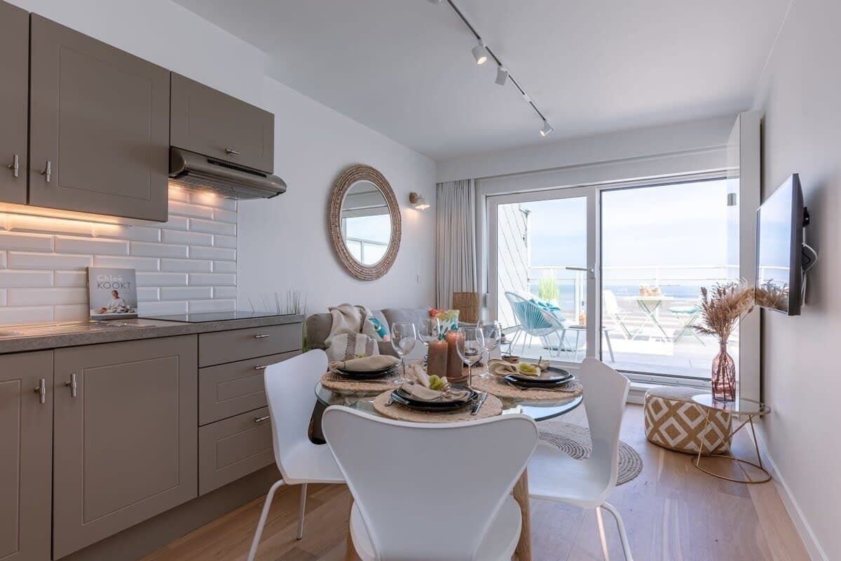 Modern kitchen and dining area with a view of the balcony and ocean beyond