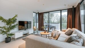 Ett modernt vardagsrum med en stor platt-TV, en soffa, ett soffbord och en krukväxt.