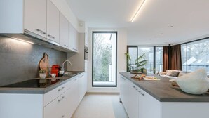 Ett modernt kök med vita skåp, en svart bänkskiva och ett stort fönster.