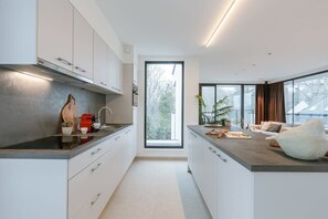 A modern kitchen with white cabinets, a black countertop, and a large window. - Light-filled 2BR retreat w/ two terraces (Zedelgem)