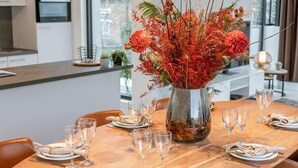 Ett matbord dukat med tallrikar, glas och en bordsdekoration bestående av röda blommor.