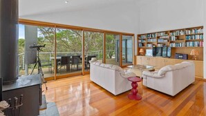 A modern living room with a fireplace, white sofas, a glass coffee table, and a bookshelf. - Panorama at Rosedale (Rosedale)