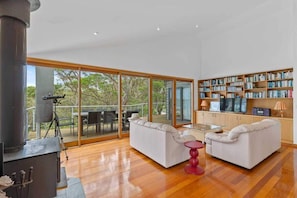 A modern living room with a fireplace, white sofas, a glass coffee table, and a bookshelf. - Panorama at Rosedale (Rosedale)
