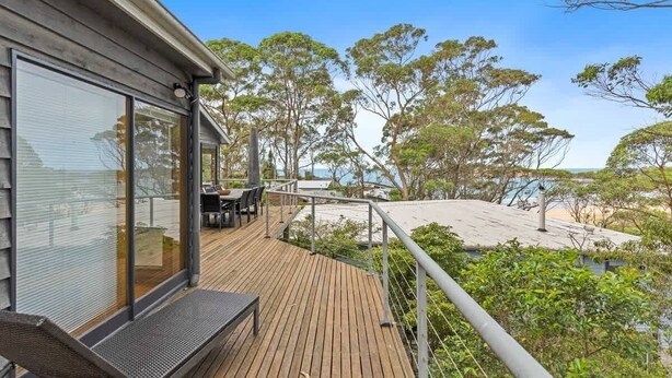 A wooden deck with a table and chairs, overlooking a beach and trees. - Panorama at Rosedale (Rosedale)
