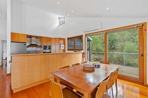 Una cocina moderna con armarios de madera, un refrigerador de acero inoxidable y un ventanal con vistas a la vegetación.