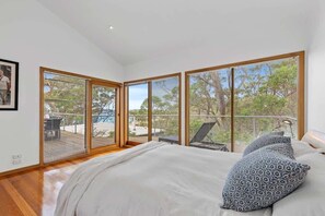 Un dormitorio con una cama grande, vistas al exterior y un balcón con una silla.
