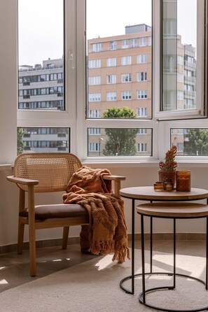A room with a large window, a wooden chair with a blanket, a small round table with candles, and a potted plant. - Beachside retreat near Oostende casino (Oostende)