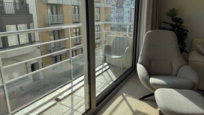 A room with a large window, a chair, and a potted plant. - Waterfront apartment w/ beach access & balcony (Knokke-Heist)