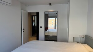 A hotel room with a bed, a door leading to a balcony, and a mirror reflecting the room. - Waterfront apartment w/ beach access & balcony (Knokke-Heist)