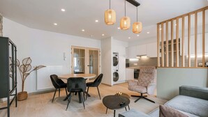Ein modernes Wohnzimmer mit Essbereich, Küche und Treppe.