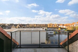 A rooftop terrace with a glass balustrade, a view of the surrounding neighborhood, and a clear sky. - Cozy 3BR apartment w/ kitchen & balcony (Knokke-Heist)