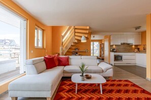 Un salon moderne avec un canapé, une table basse et un escalier menant à l’étage supérieur.