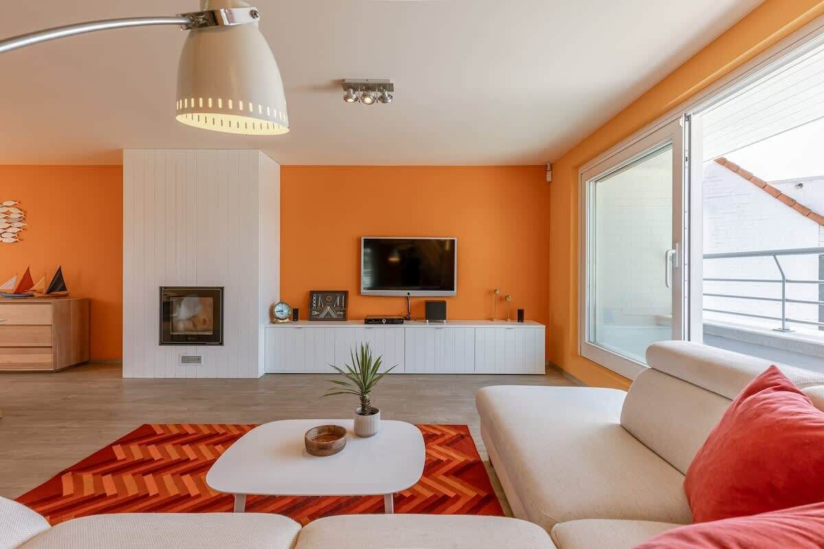 A modern living room with a sofa, a coffee table, a fireplace, a TV, and a large window.