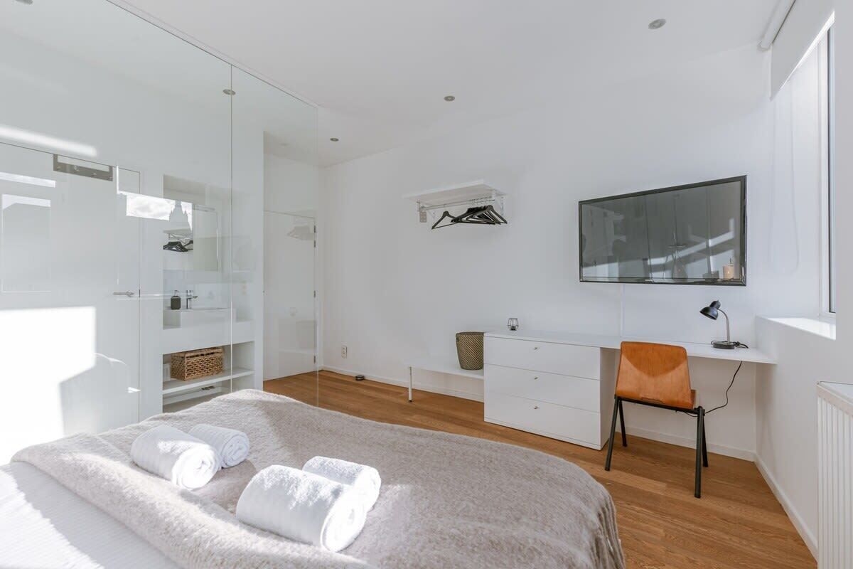 Ein modernes Schlafzimmer mit Bett, Schreibtisch, Stuhl, Kleiderschrank und Fernseher.