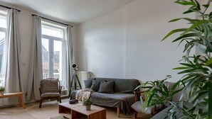Una sala de estar con sofá, sillones, una mesa de centro y un trípode.