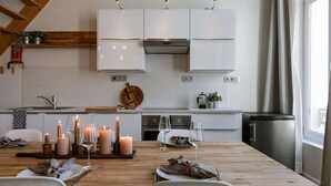 Una cocina moderna con armarios blancos, una mesa de comedor de madera preparada para dos personas y velas.