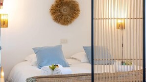 Et soveværelse med seng, puder, vægdekoration og en lampe.