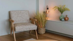 A room with a wooden chair, a woven floor lamp, a small table, and a potted plant. - Coastal getaway w/ full kitchen & workspace (Knokke-Heist)
