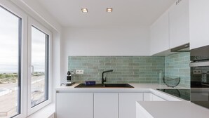 A modern kitchen with a large window, a sink, and a backsplash. - Coastal getaway w/ full kitchen & workspace (Knokke-Heist)