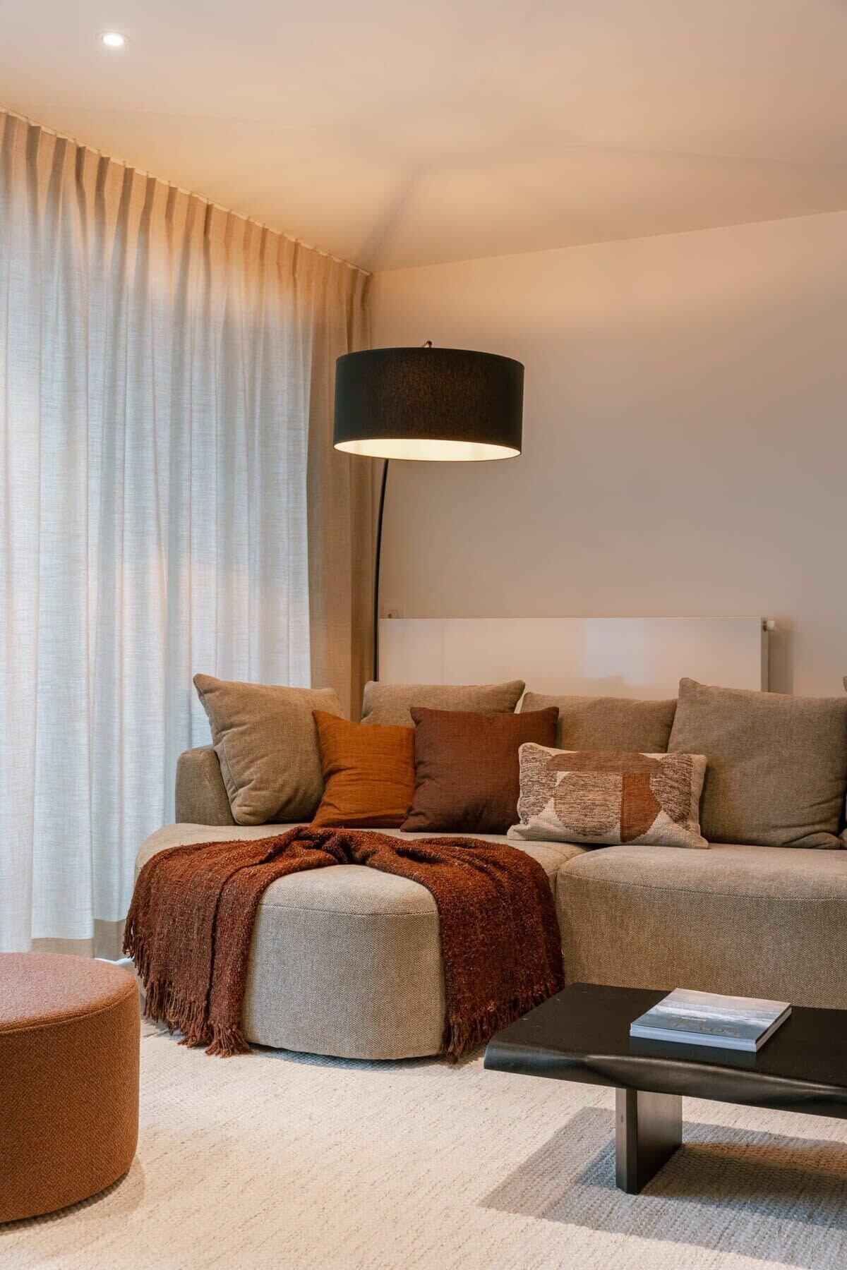 Ein stilvolles Wohnzimmer mit einer Couch, einem Hocker und einem Couchtisch.
