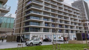 Ein mehrstöckiges Gebäude mit Balkonen, einem Parkplatz und einem Rasen im Vordergrund.