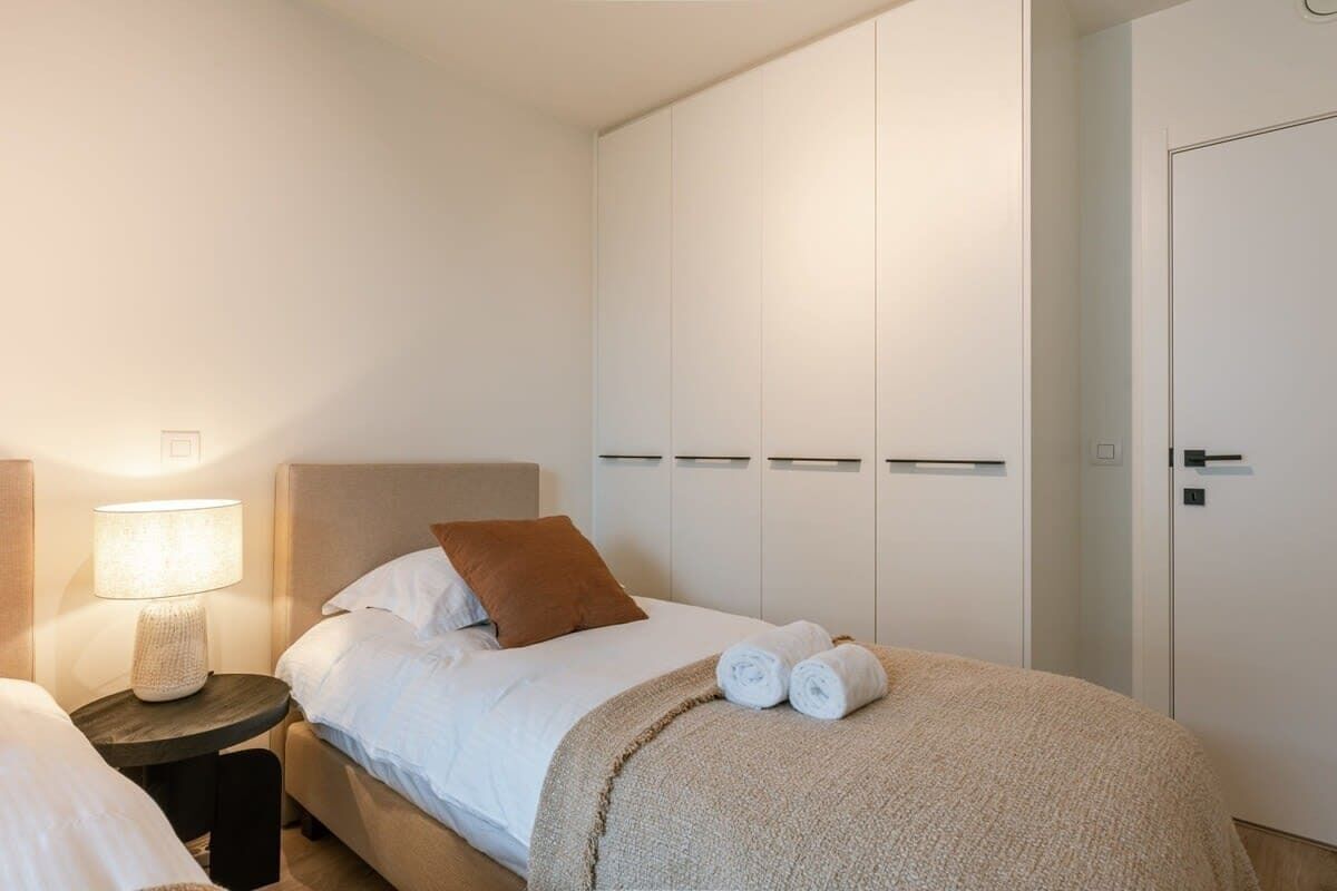 Une chambre d’hôtel avec un lit, une table de chevet avec une lampe, une armoire et une porte.