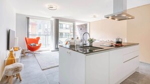 Een moderne keuken met een centraal eiland, een inbouwoven en een groot raam.