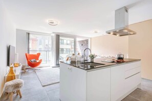 Une cuisine moderne dotée d’un îlot central, d’un four encastré et d’une grande fenêtre.