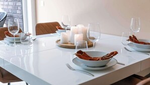 Een gedekte eettafel met kaarsen, borden en glazen.