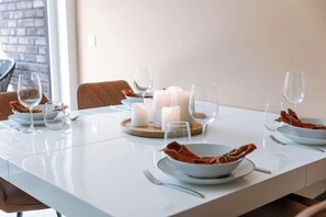 Une table à manger dressée avec des bougies, des assiettes et des verres.