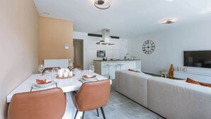 Een moderne eethoek met een witte tafel, bruine stoelen en een keuken op de achtergrond.