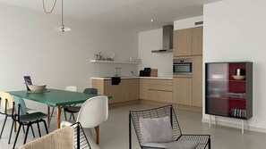 Eine moderne Küche mit Essbereich, inklusive Tisch, Stühlen und einem Schrank mit Regalen.